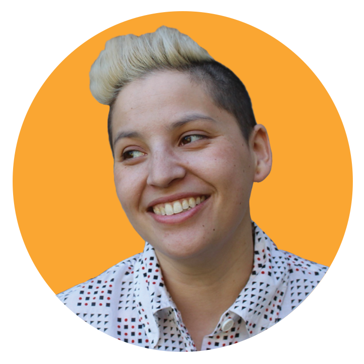 Person with short dark hair and a light blonde streak smiles and looks to the side, wearing a white patterned shirt. Set against a solid orange background in a circular frame, the image reflects the vibrant and dynamic energy of a creative agency. Person with short dark hair and a light blonde streak smiles and looks to the side, wearing a white patterned shirt. Set against a solid orange background in a circular frame, the image reflects the vibrant and dynamic energy of a creative agency.
